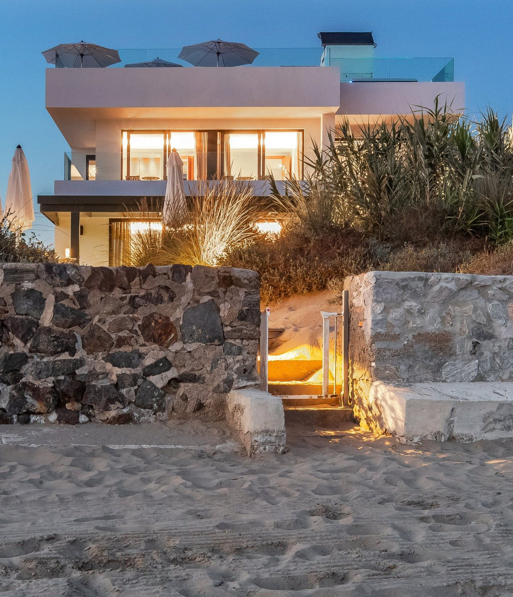 Frontline beach house lit at dusk above the sand in Elviria, Marbella