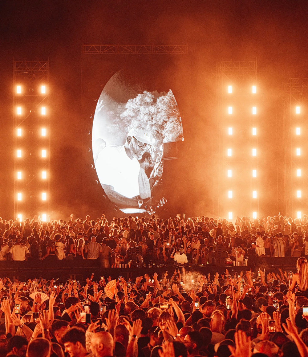 Crowd under orange stage lights at a summer concert in Marbella