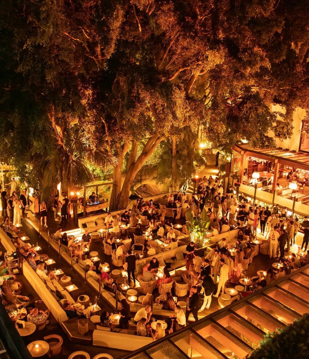 Evening crowd under the trees at La Plaza, Puente Romano, Marbella