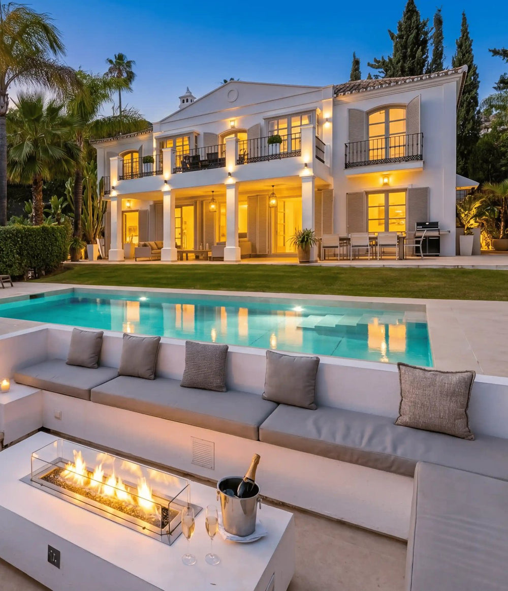 Villa lawn, pool and fire-pit lounge lit at dusk, Marbella